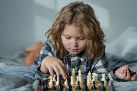 Foto de Kid play chess at home. Chess school. Child think about chess game. Intelligent, smart and clever school kid pupil. Games for brain intelligence concept - Imagen libre de derechos