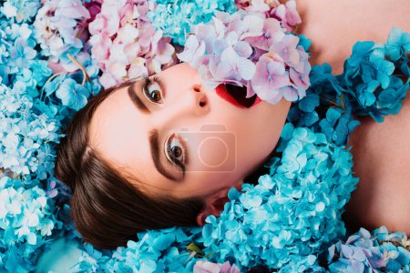 Foto de La belleza natural. Mujer acostada sobre flores. Unidad con la naturaleza. Blossom. Maquillaje cosmético y cuidado de la piel. Chica con flores de hortensias - Imagen libre de derechos