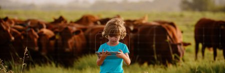 Foto de Niña agricultora en granja de vacas. Niños en el campo. Niño con tableta en la granja - Imagen libre de derechos