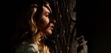 Photo for Portrait of beautiful spy young woman. Outdoor portrait of a cute girl. Woman face in shadow - Royalty Free Image