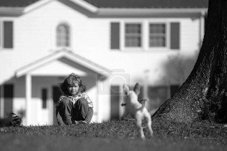 Foto de Niño lindo jugando con el perro chihuahua en el césped del patio trasero - Imagen libre de derechos