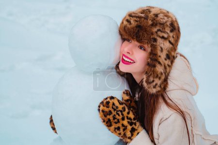 Téléchargez les photos : Portrait d'hiver de jeune belle femme dans le jardin des neiges faire bonhomme de neige. Bonne femme portrait d'hiver. Bonne période hivernale - en image libre de droit