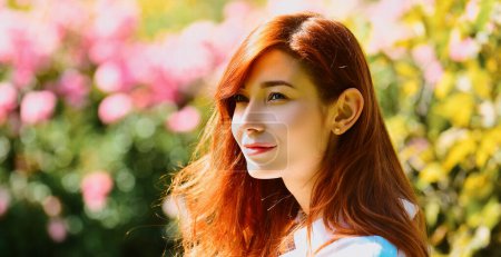 Photo for Spring design with beautiful woman face for banner or website header, copy space. Close up portrait of a beautiful red haired girl in spring park. Pretty model between pink roses. Spring blossom - Royalty Free Image