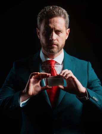 Téléchargez les photos : Bel homme d'affaires mature avec carte de crédit isolé sur fond noir - en image libre de droit
