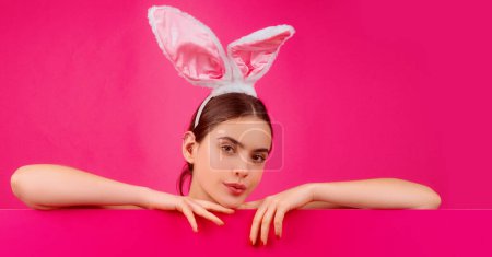 Téléchargez les photos : Bannière de Pâques avec lapin femme. Publicité de Pâques. Une fille aux oreilles de lapin. Lapin femme avec panneau de couleur - en image libre de droit