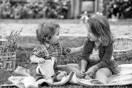 Téléchargez les photos : Des enfants au pique-nique. Joyeux enfant dans le parc. Soeur nourrissant un petit garçon. La fille nourrit son frère avec une cuillère. Nourriture pour enfants - en image libre de droit