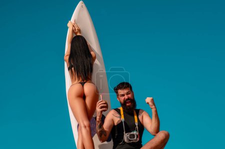 Téléchargez les photos : Vacances d'été. Femme sexy en bikini. Concept d'été. Homme sexy en maillot de bain. Une planche de surf. Gagnant de la vie - en image libre de droit