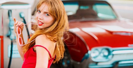 Photo for Pretty woman refuel the car. Gas station. Elegant lady against red retro automobile - Royalty Free Image