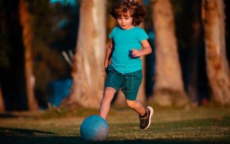 Téléchargez les photos : Enfant garçon jouant au football sur le terrain de football. Un gamin qui joue au foot. Jeunes enfants sportifs - en image libre de droit