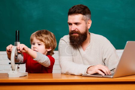 Photo for Man teacher play with preschooler child. Homeschooling. Teacher and schoolboy using laptop in class. Young or adult. Teacher helping kids with their homework in classroom at school - Royalty Free Image