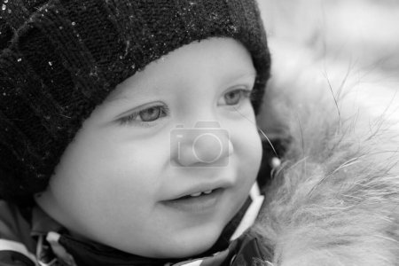 Foto de Primer plano retrato de niño feliz en sombrero de invierno. Divertido niño lindo feliz en el parque de invierno. Clima frío nevado. Increíble parque de invierno. Hermosa naturaleza de invierno - Imagen libre de derechos