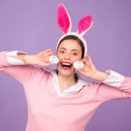 Téléchargez les photos : Belle jeune femme avec des oreilles de lapin sur fond de couleur studio. Pâques femme drôle avec des oreilles de lapin. Portrait d'une jolie fille aux oreilles de lapin - en image libre de droit