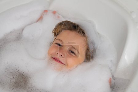 Foto de Kids face in foam. Child bathes in a bath with foam - Imagen libre de derechos