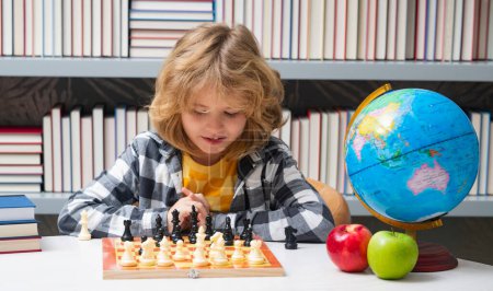 Foto de Escuela de ajedrez. Inteligente niño concentrado y pensante jugando ajedrez. Niño niño desarrollando estrategia de ajedrez, juego de mesa - Imagen libre de derechos