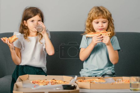 Photo for Hungry kids eating pizza. Two young children bite pizza indoors - Royalty Free Image