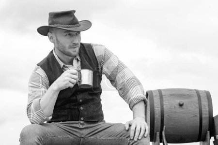 Photo for Handsome bearded macho man. Men beauty standard. Example of true masculinity. Cowboy wearing hat. Western life. Unshaven guy in cowboy hat and plaided shirt drinking alcohol - Royalty Free Image