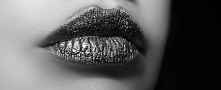 Téléchargez les photos : Des lèvres dorées. Femme sexy maquillage des lèvres isolé sur fond noir - en image libre de droit