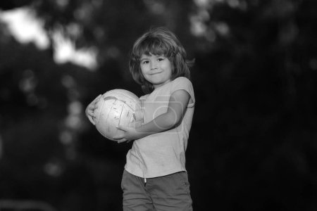 Foto de Emocionado niño pateando la pelota en el césped al aire libre. Niños de fútbol, niños juegan al fútbol. Juegos de pelota activa - Imagen libre de derechos