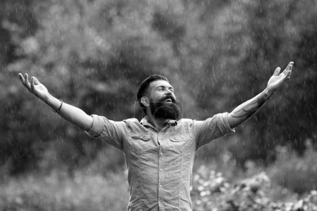 Téléchargez les photos : Il pleut. Homme sous la pluie d'été. Portrait d'homme barbu heureux insouciant sur la nature. Optimisme adulte et temps seul - en image libre de droit