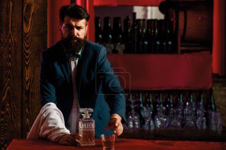 Téléchargez les photos : Barman barman barbu serveur debout sur fond de barre - en image libre de droit