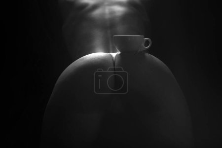 Téléchargez les photos : Sexy buttocks with coffee cup, perfect butt with coffee. Coffee cup on sexy naked ass, woman body concept. Cup on sexy womans butt on black. Erotic photo about the use of coffee drinks - en image libre de droit