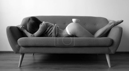 Foto de Mujer sexy con taza de café en el sofá. Lujosa chica desnuda hermosa. Torso desnudo, concepto de café por la mañana - Imagen libre de derechos