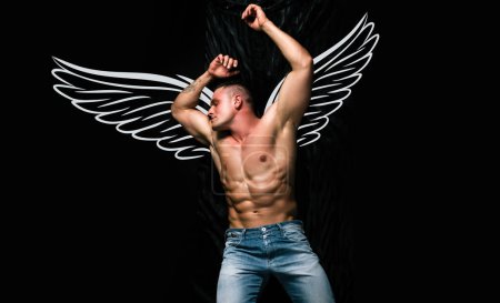 Téléchargez les photos : Naked muscular angel. Photo banner of sexy man with wings for valentines day. Wellness, wellbeing concept. Shirtless muscular bodybuilder man reading book, laying on bed. Luxury lifestyle - en image libre de droit