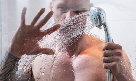 Foto de Shower. Guy taking shower in bathroom. Relaxing time. Fresh shower. Good looking man is under water drops - Imagen libre de derechos