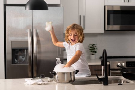 Foto de Niños emocionados lavando platos con agua y jabón cerca del fregadero en la cocina - Imagen libre de derechos