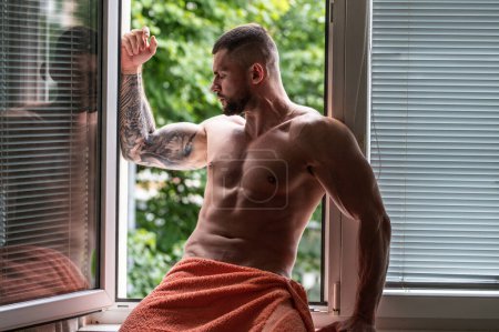 Foto de Sexy and naked muscular young man posing on window curtains. Sexy shirtless male model. Attractive young naked man body. Romantic dreaming nude male model with sexy body - Imagen libre de derechos