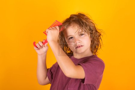 Foto de Boy brushes his hair. Child with brush combing hair. Boy taking hairstyle. Child brushing hair with comb, kids haircare - Imagen libre de derechos