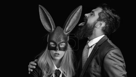 Téléchargez les photos : Masque lapin femme. Un homme sérieux avec une barbe. Lapin et fille. Belle femme en costume de lapin. Un homme élégant. Jeune fille Pâques femme dans les oreilles de lapin - en image libre de droit