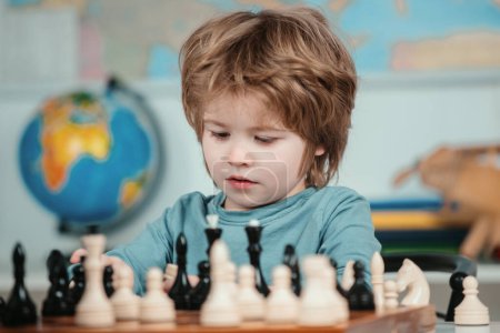 Foto de Niño pequeño con ajedrez. Niño concentrado sentado en la mesa y jugando al ajedrez. Escuela de ajedrez - Imagen libre de derechos