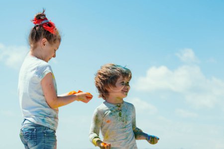 Téléchargez les photos : Les enfants drôles jouent avec les peintures en plein air. Portrait d'un mignon enfant peint aux couleurs du festival Holi - en image libre de droit