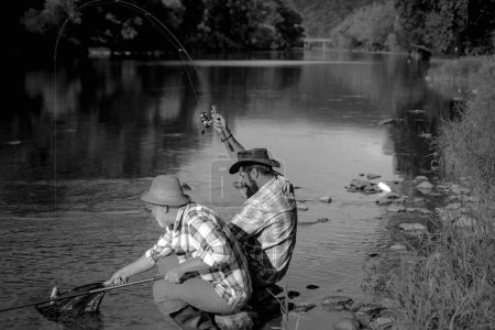 Foto de Retrato de dos hombres alegres pescando. Pesca con mosca. Un fin de semana perfecto. Se fue a pescar. Hora del fin de semana. Pescador con caña. Unidos con la naturaleza. En el lago - Imagen libre de derechos