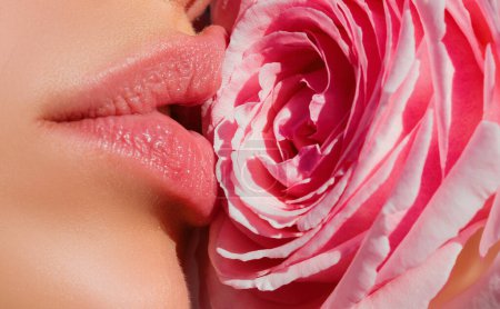 Foto de Woman kissing red rose flower. Lips with lipstick closeup. Beautiful woman lips with rose - Imagen libre de derechos