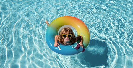Foto de Vacaciones infantiles de verano. Fin de semana. Un chico en la piscina. Un chico en Aquapark. Chico gracioso en círculo de goma inflable - Imagen libre de derechos
