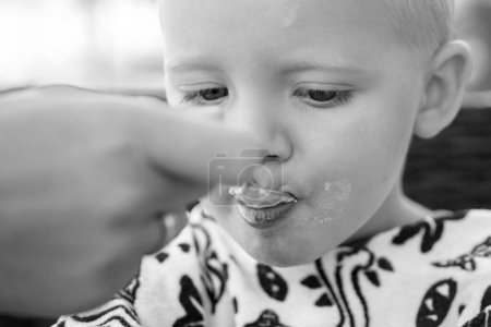 Téléchargez les photos : De la nourriture pour enfants. Nourrir bébé garçon avec une cuillère. Paternité, mère ou sœur avec enfant - en image libre de droit