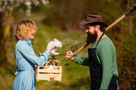 Téléchargez les photos : Portrait d'un jeune couple heureux en cour pendant la saison printanière. Un jardinier. Plantation de cultures dans les champs - en image libre de droit