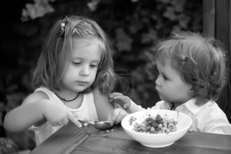 Foto de Nutrición infantil. Niña alimentando al niño. La hermana alimenta al hermano. Relaciones con niños - Imagen libre de derechos
