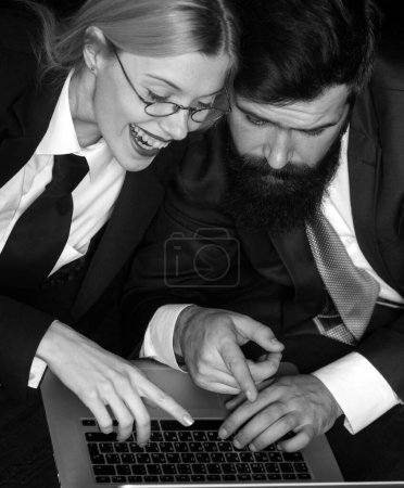 Foto de Dos socios de negocios trabajando juntos con el portátil. Mujer de negocios sonriente y su colega mirando el portátil. Un par de jóvenes diseñadores trabajando en el portátil - Imagen libre de derechos