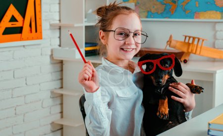 Photo for Cute playful doggy or pet with glasses looking up like a pupil. Funny puppy in glasses. Happy smiling kid go back to school. Funny education. Smart and clever dog with glasses - Royalty Free Image