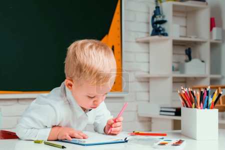 Photo for Cute little preschool kid boy with teacher study in a classroom. Learning and education concept. Home school for pupil. 3 year old child. - Royalty Free Image