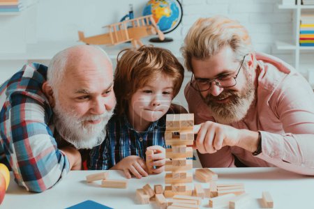Photo for Three generations of active men playing in living room. Laughing grandparent with son and grandchild relaxing spending weekend at home - Royalty Free Image