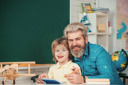 Photo for Father teaching son. School community partnership. Happy school kids at lesson. Kid and teacher is learning in class on background of blackboard - Royalty Free Image