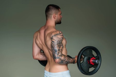 Foto de Muscular man lifting weights at gym. Handsome guy prepare to do exercises with dumbbell - Imagen libre de derechos