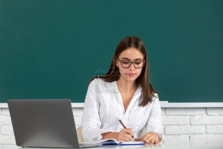 Photo for Portrait of young female college student studying in classroom on class with blackboard background, online learning at school, distance education - Royalty Free Image