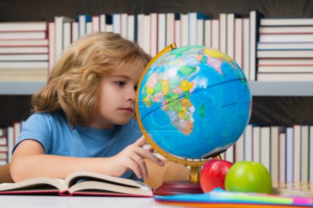 Téléchargez les photos : School kid looking at globe in library at the elementary school. Child from elementary school. Pupil go study. Clever schoolboy learning. Kids study, knowledge and education concept - en image libre de droit