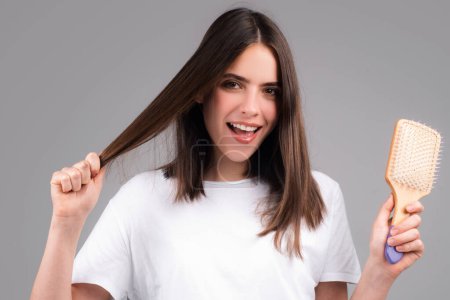 Foto de Retrato de una hermosa joven peinándose el pelo, sonriendo. Cepillado femenino cabello sano con peine. Se preocupa por un cabello sano y limpio. concepto de salón de belleza - Imagen libre de derechos