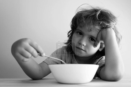 Foto de Pequeño niño descontento no quiere comer una pasta con chuleta. El niño no quiere comer.. - Imagen libre de derechos